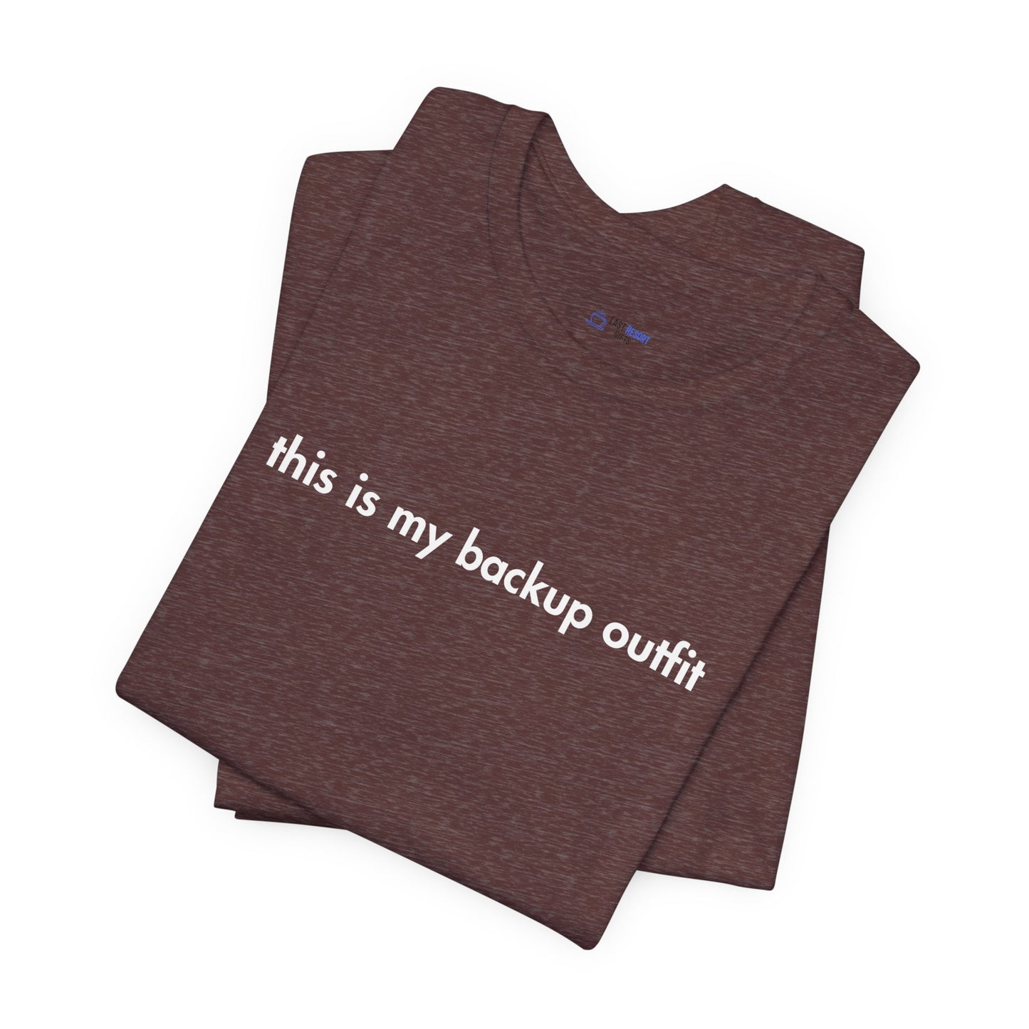 Folded brown t-shirt with 'this is my backup outfit' text on a white background